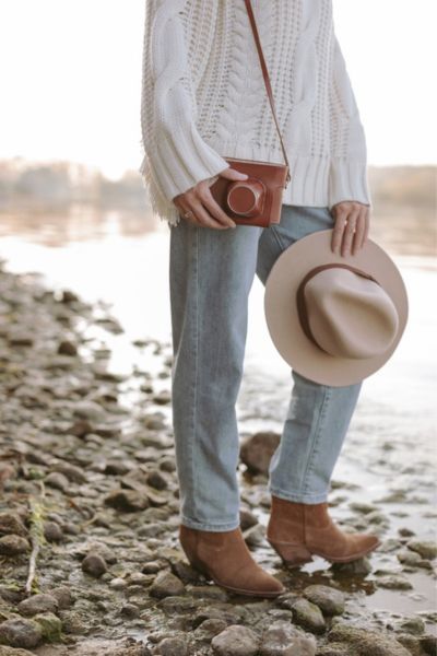A woman wears jeans with white shirt and cowboy boots