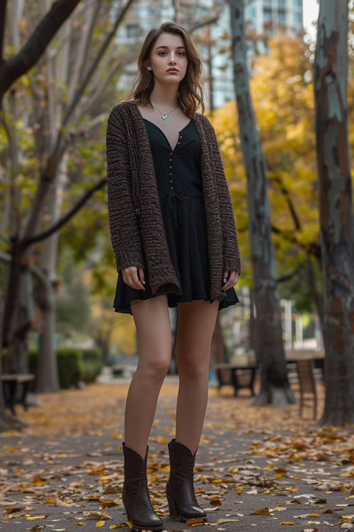 a woman wears a dark cardigan, a black dress with ankle cowboy boots