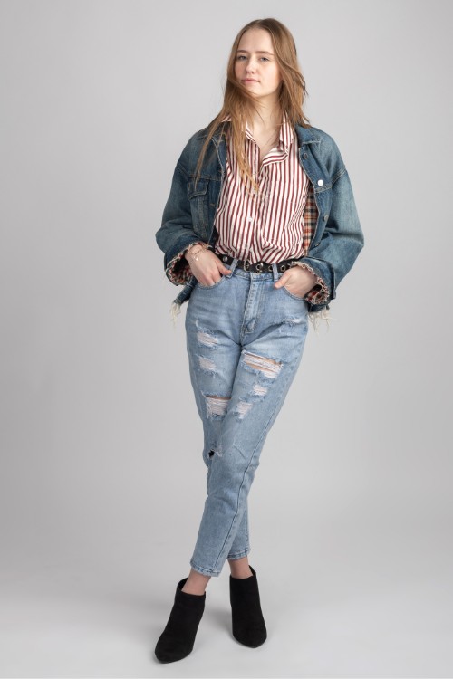 A woman wears ripped jeans, striped top and denim coat with ankle cowboy boots