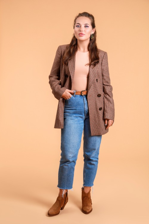 a woman wears ankle cowboy boots with ripped jeans, a blazer and a nude fitted top