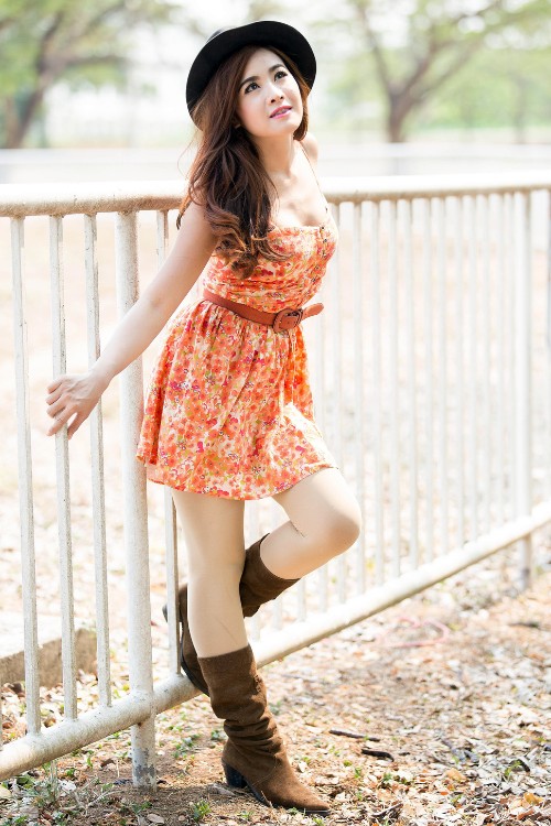 A woman wears brown cowboy boots with a floral dress
