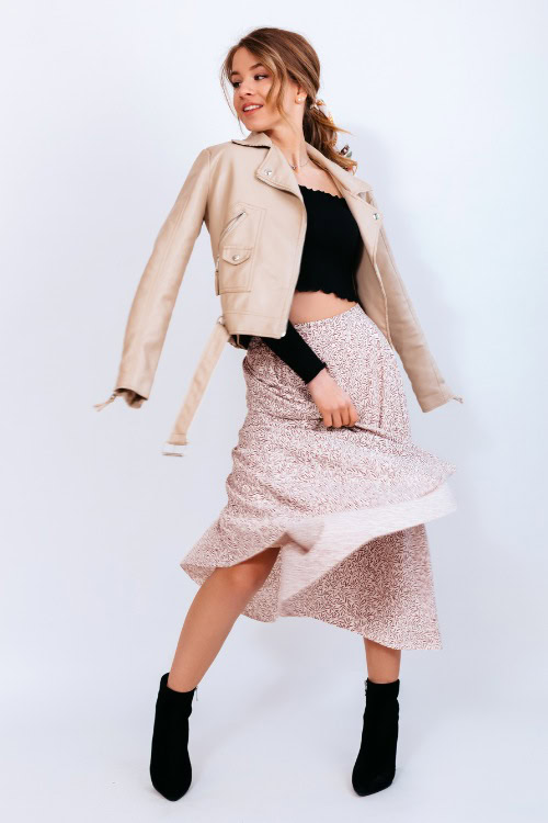 A woman wears cowboy boots with a mini top, skirt and coat