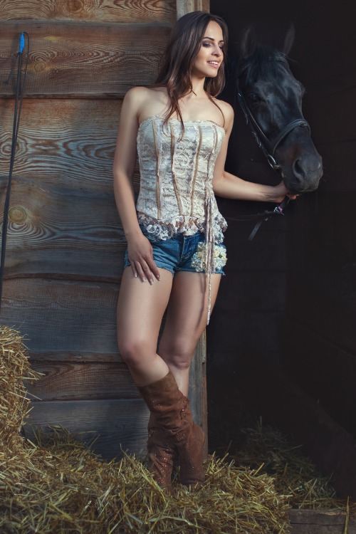 A woman wears brown cowboy boots with shorts and an off-shoulder top.