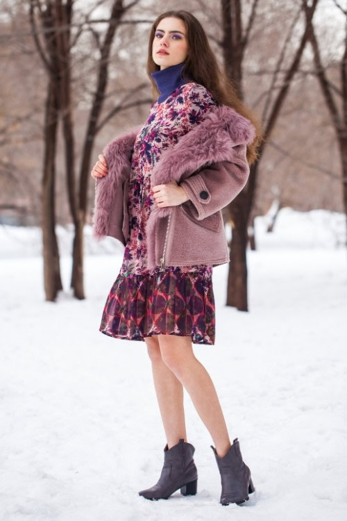 a woman wears ankle cowboy boots with a ruffle pattern dress and fur coat in the winter