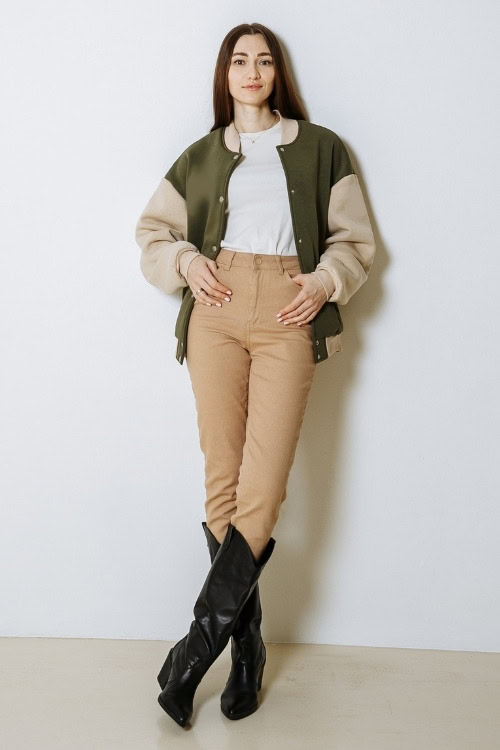 a woman wears black cowboy boots with brown pants and green bomber jacket