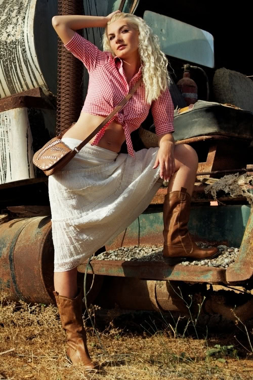 a woman wears brown cowboy boots with a skirt