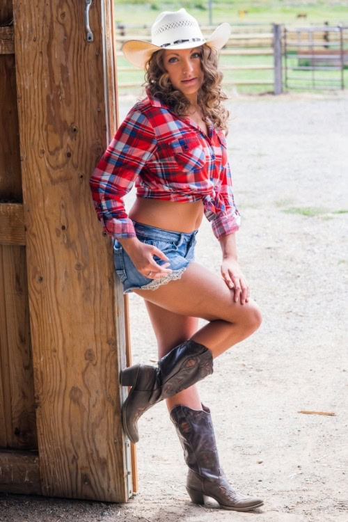 a woman wears cowboy boots with shorts and a shirt
