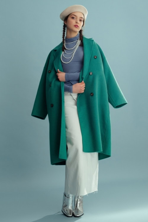 a woman wears elegant outfit with teal trench coat, long skirt and silver cowboy boots