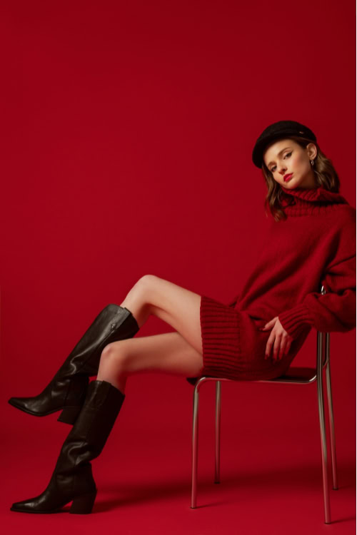 a woman wears red sweater dress with cowboy boots