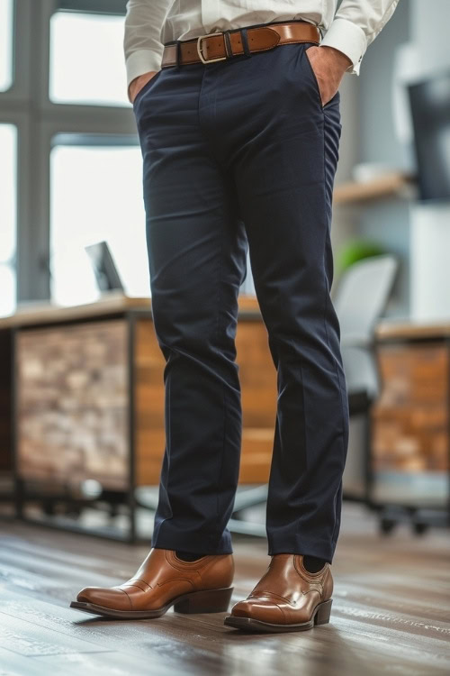 a man wears brown cowboy boots, a shirt, and navy pants