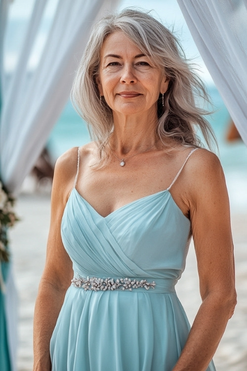 A woman over 50 wears a blue wedding guest dress with thin straps