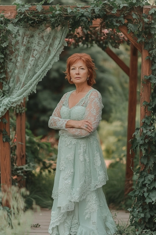 A woman over 50 wears a mint green layered lace wedding guest dress with long sleeves