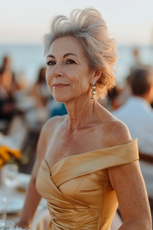 A woman over 50 wears a yellow satin wedding guest dress with a one shoulder design