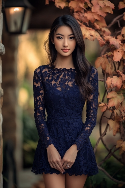 A woman wears a navy blue lace wedding guest dress with long sleeves and a high neckline