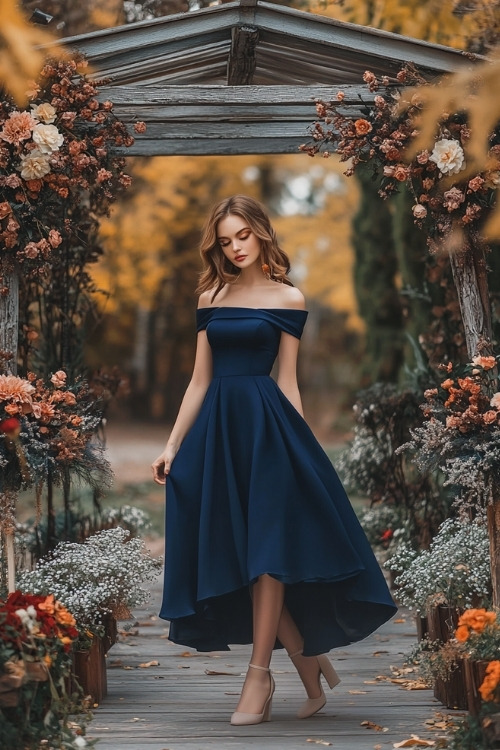 A woman wears an off shoulder navy wedding guest dress with beige heels