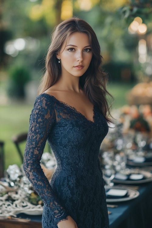 a woman wears a V neck navy blue lace wedding guest dress with long sleeves