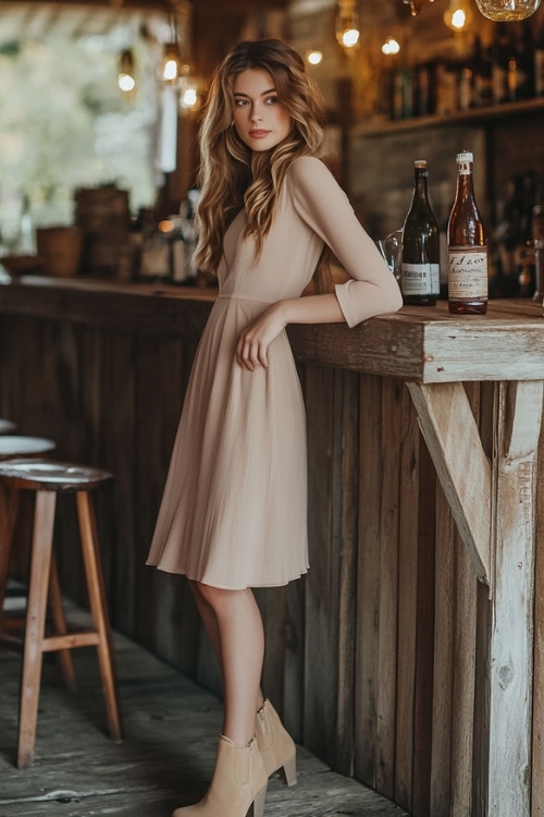 a woman wears a long sleeve beige burgundy wedding guest dress with matching boots