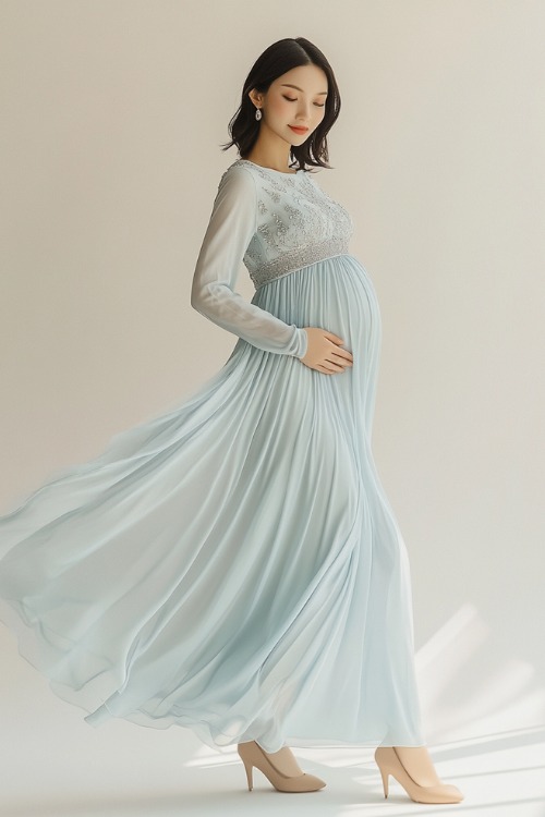 A chic winter maternity outfit featuring a long-sleeve empire-waist maternity dress in icy blue chiffon with subtle silver embroidery on the bodice