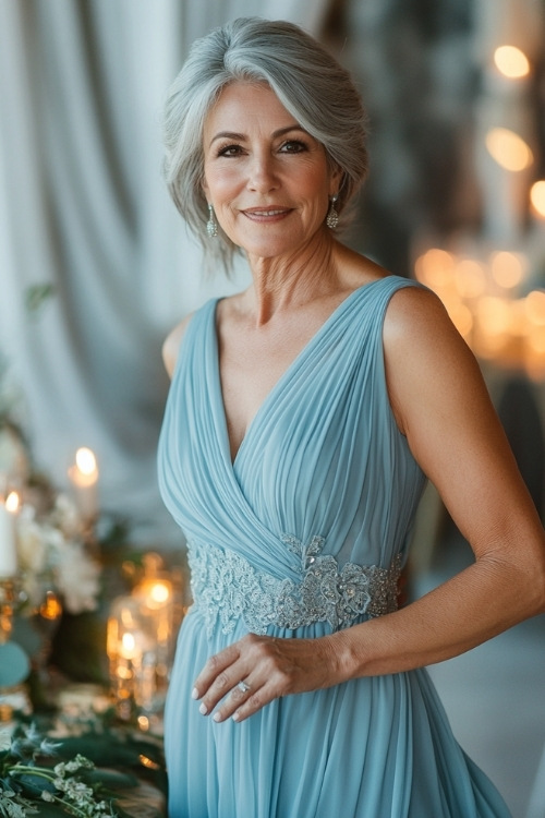 A stylish woman over 50 in a pastel blue sleeveless midi dress with a pleated hemline, lace accents, and a flowing bodice