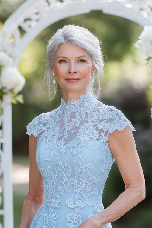 A petite woman over 50 in a pastel blue fit-and-flare dress with a high neckline and lace details