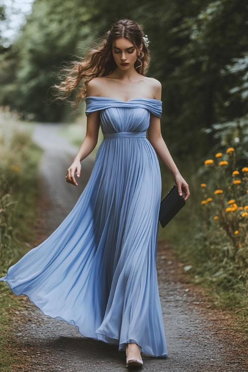 A woman in a periwinkle blue chiffon maxi dress with subtle pleating, holding a small clutch while walking through a charming countryside wedding venue