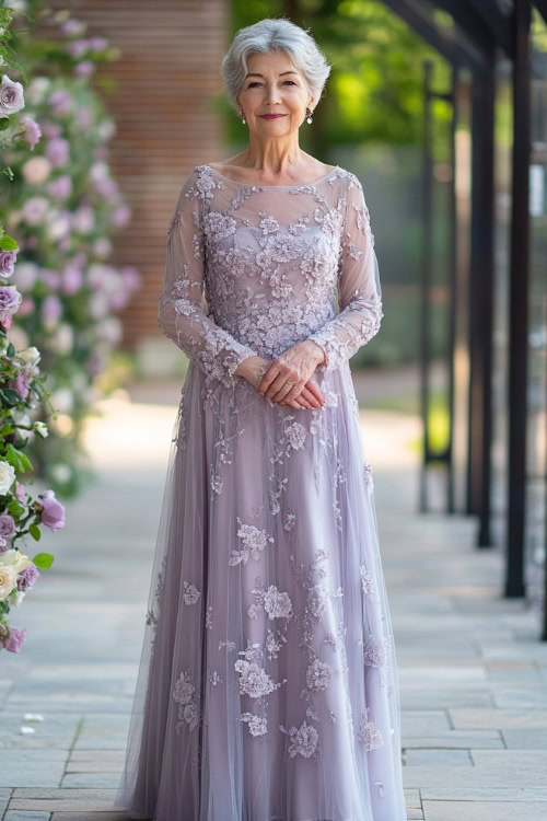 A woman over 50 in a soft lilac floor-length dress with floral embroidery and sheer long sleeves