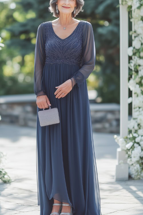 A woman over 50 in an elegant navy blue chiffon gown with long sheer sleeves and delicate beading on the bodice