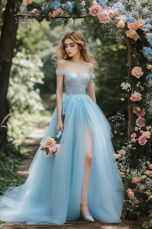 A woman in a light blue knee-length dress with a fitted lace bodice and a voluminous tulle skirt, standing beside a floral arch at a spring garden wedding